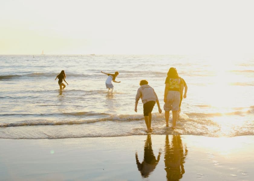 family walking into shallow ocean water at sunset family walking into shallow ocean water at sunset
